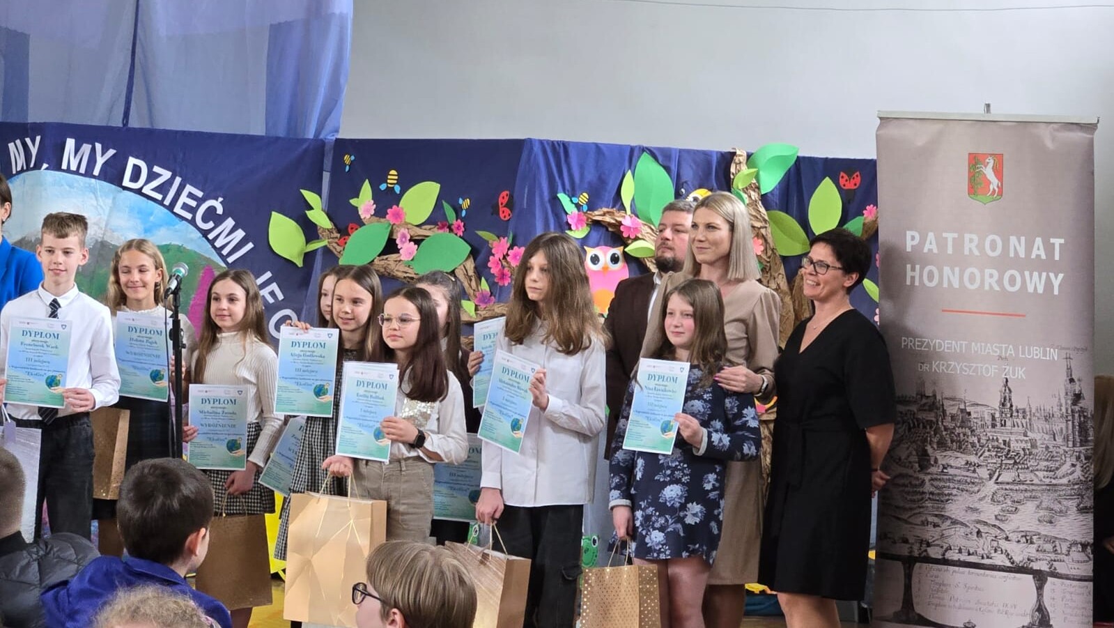 na scenie stoją dzieci, trzymają w rękach dyplomy otrzymane w konkursie EkoGra.