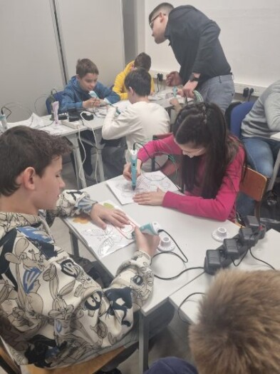 Uczniowie klasy 5c siedzą przy stolikach i wykonują prace używając długopisów 3D.