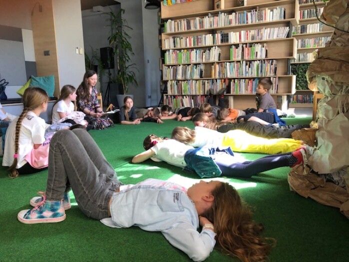 Uczniowie leżą na dywanie i relaksują się podczas czytania.